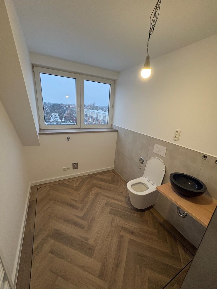 Badsanierung Hamburg – Gäste-WC mit Fischgrätparkett, Wandfliesen Betonoptik und schwarzem Aufsatzbecken