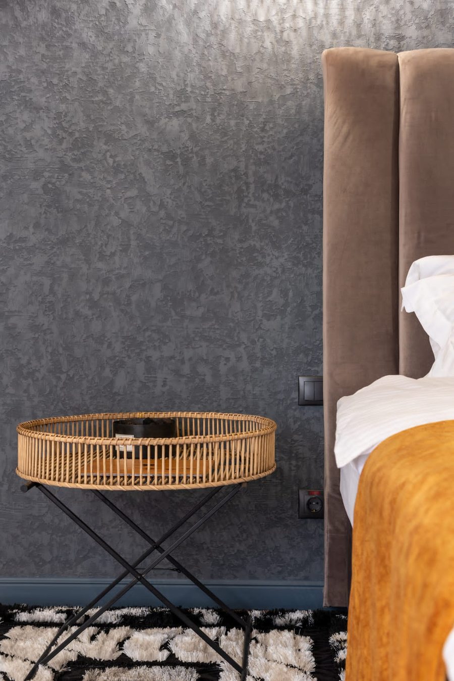 Schlafzimmer Wandgestaltung Hamburg – anthraziter Spachtelputz strukturiert mit Rattan-Beistelltisch